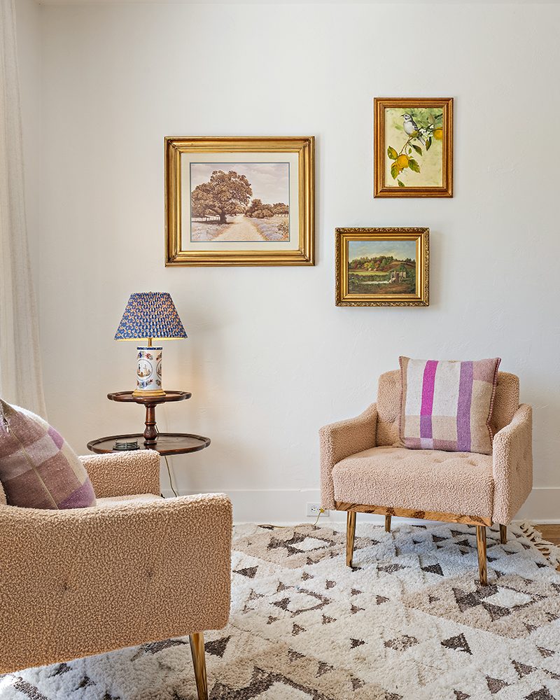 Sitting area with boucle chairs and a gold-framed gallery wall
