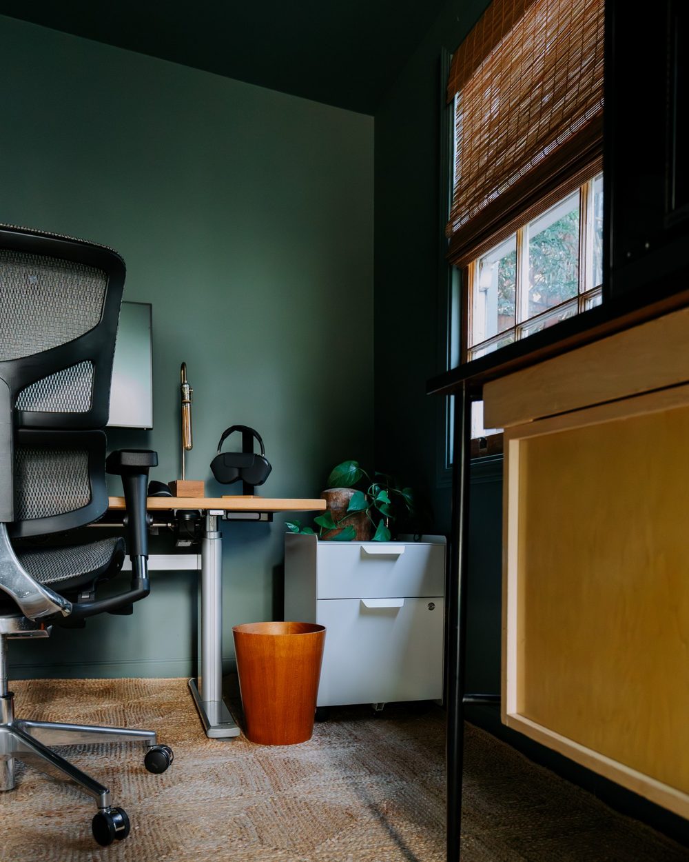 Desk corner with woven blinds, filing cabinet and teak wastebasket